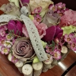 Zongorán négyzet alakú virágtartó lila és rózsaszín virágokkal.