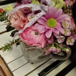 Zongora billentyűin, szürke bögre, rózsaszín és sárga virágokkal.