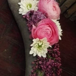Egy hajlított széles faágon fehér és rózsaszín virágokból és lila bogyós virágból készült csokor van.