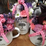 Aromatic Coffee feliratú fehér bögrékben kék és rózsaszínű virágok.