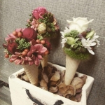 Fagyi tölcsér formájú vázák, piros, zöld és fehér színű virágokkal.